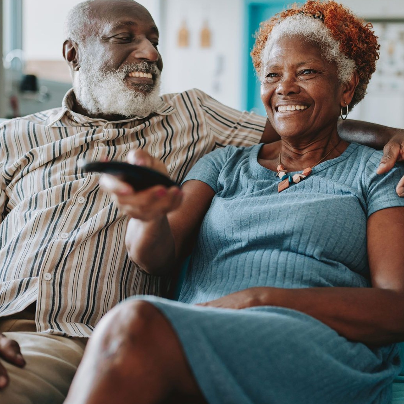 a man and woman sitting on a couch watching TV